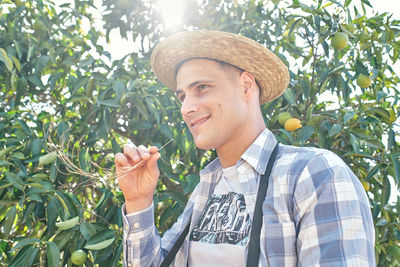 Portrait of smiling man with apple against trees