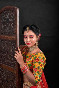 Portrait of young woman standing against wall