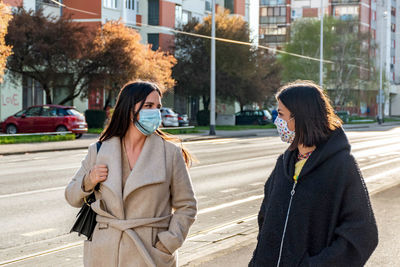 Two friends walking in city, wearing protective masks during corona virus epidemic, female, women.