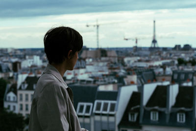 Man looking at city buildings against sky