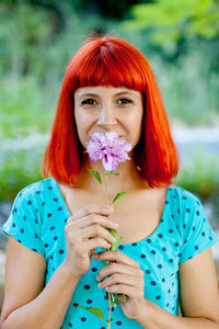 Portrait of beautiful woman holding flower standing outdoors