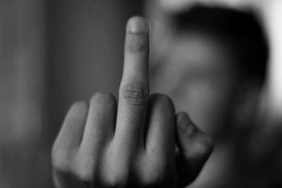 Cropped hand of man showing middle finger