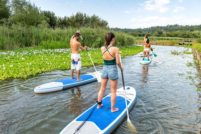 Full length of friends paddleboarding on lake