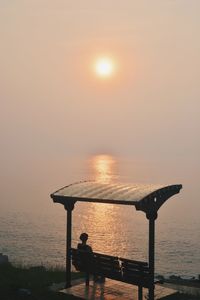 Silhouette man fishing by sea against clear sky during sunset