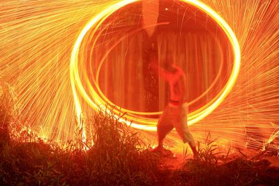 Blurred motion of young woman with fire crackers at night