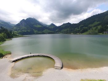 Scenic view of lake and mountains against cloudy sky