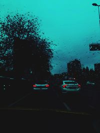 Cars on road seen through wet windshield