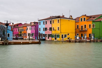 Houses by water against clear sky