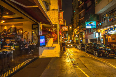 Illuminated road amidst buildings in city at night