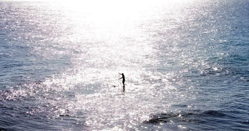 Silhouette person in sea against sky