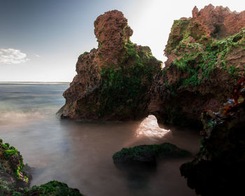 Rock formations by sea against sky