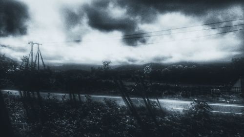 Trees and electricity pylon against sky