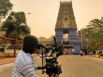 Rear view of woman standing against sky in city at sunset