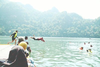 People swimming in mountains against sky