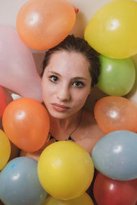 Portrait of woman with colorful balloons at home