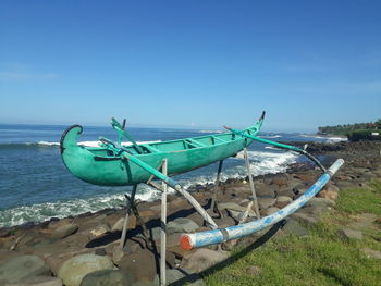 Ship moored on beach against blue sky