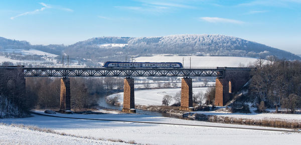 Road by river against sky during winter