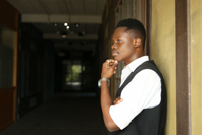 Boy looking away while standing in corridor