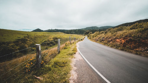 Dirt road along landscape against sky