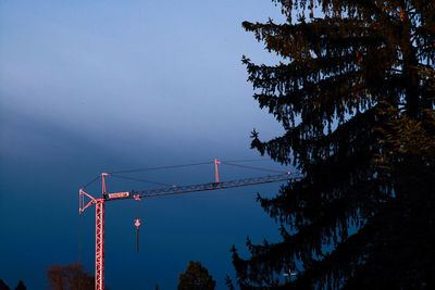 Low angle view of silhouette crane against sky at dusk