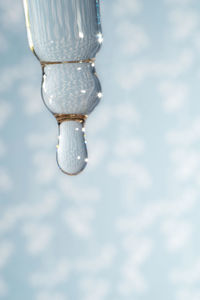 A dripping pipette with a drop of cosmetics gel.