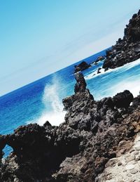 Rock formations on shore against blue sky