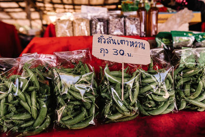 From above of green peas pods in packages on shelf with price tag in outdoors market in thailand