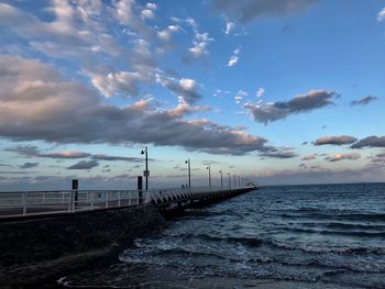 Pier over sea against sky during sunset