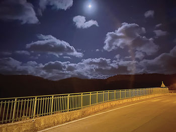 Bridge over road against sky at night