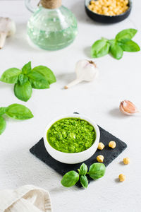 Homemade pesto sauce in a bowl and ingredients on the table. healthy italian cuisine. vertical view