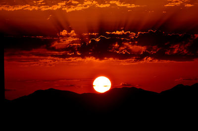 Scenic view of silhouette mountains against orange sky