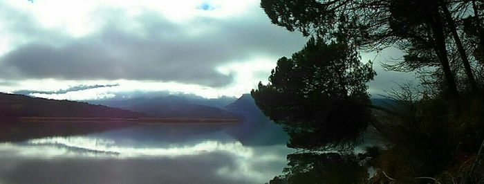 Scenic view of calm lake against cloudy sky