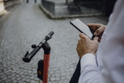 Businessman renting an e-scooter using smartphone