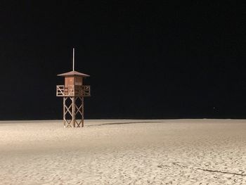 Built structure on beach against sky at night