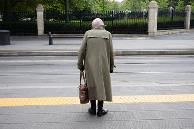 Rear view of man walking on sidewalk