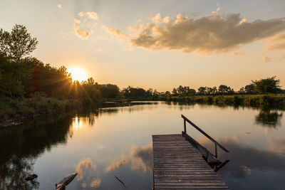 Pier over lake against sky during sunset