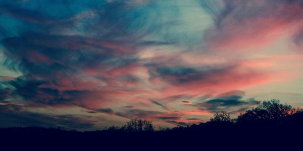 Low angle view of silhouette trees against dramatic sky