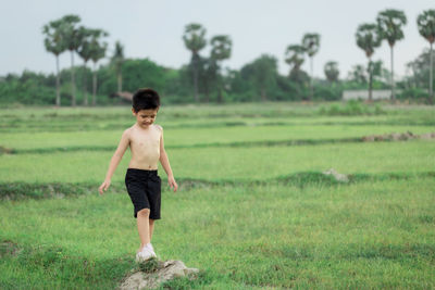 Full length of shirtless boy standing on field