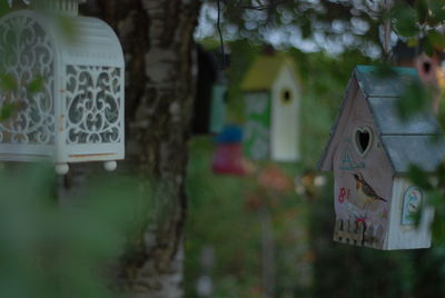 Close-up of birdhouse hanging against trees and building