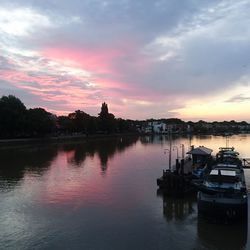 Boats moored in lake against sky during sunset