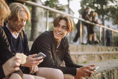 Cheerful teenage boys sitting with smart phones