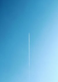 Low angle view of vapor trail against blue sky