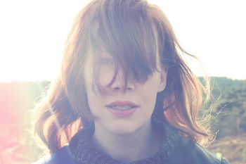 Portrait of woman with tousled hair against sky