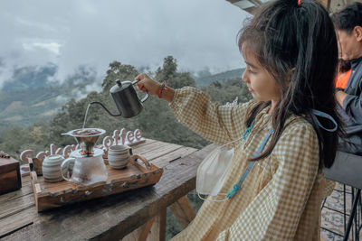 Little girl making drip coffee with a beautiful mountain