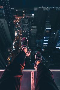 Low section of man and illuminated buildings in city at night