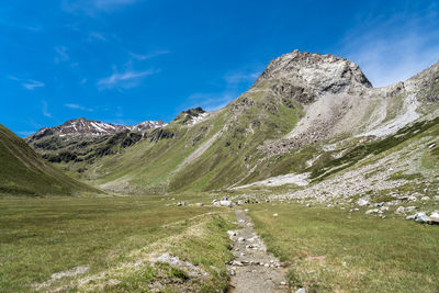 Scenic view of land and mountains against blue sky