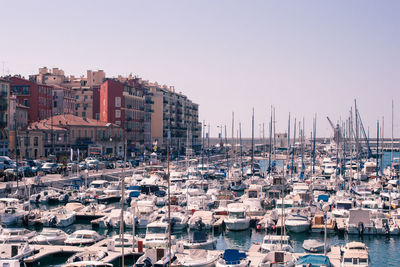 Sailboats moored at harbor against clear sky