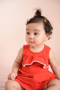 Portrait of cute girl sitting on wall at home