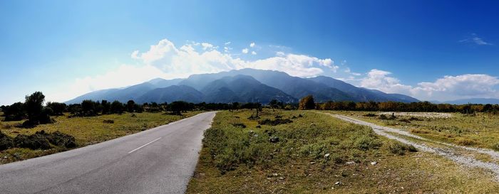 Road leading towards mountains against sky