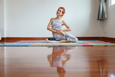 Full length of young woman exercising at home